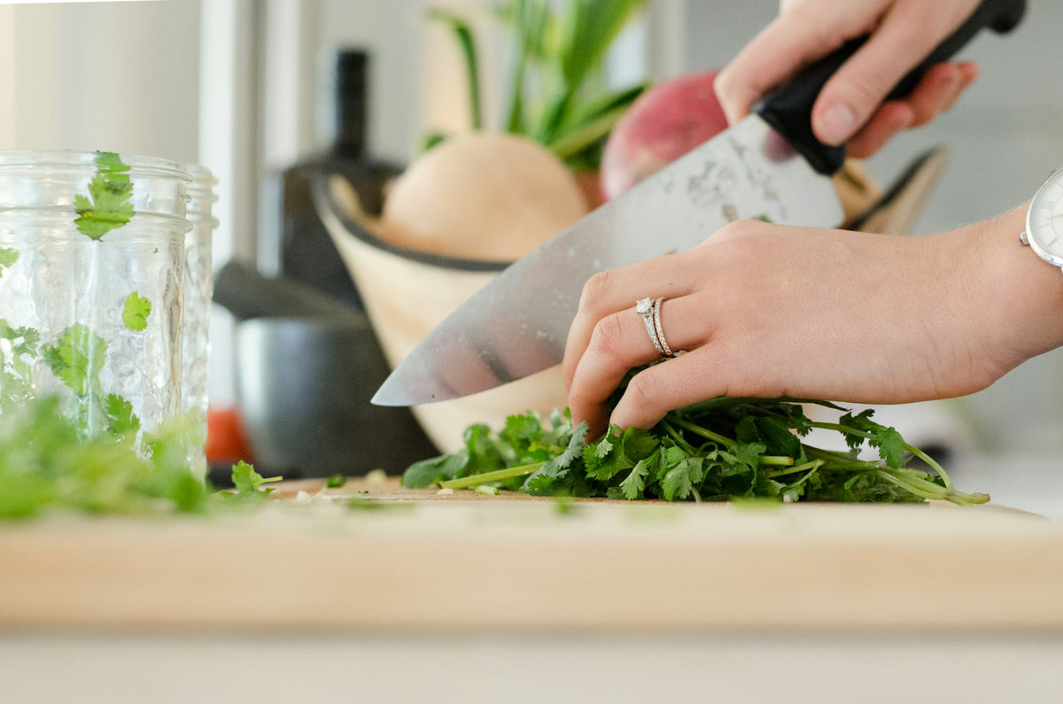 Hands chopping fresh herbs on a wooden board